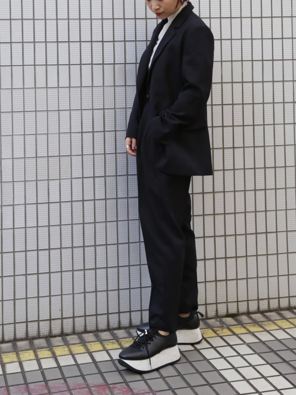 ブラック系のテーラードジャケット、ブラック系のその他パンツ、ホワイト系のスニーカーを着用したレディースの冬コーディネートの2枚目の写真