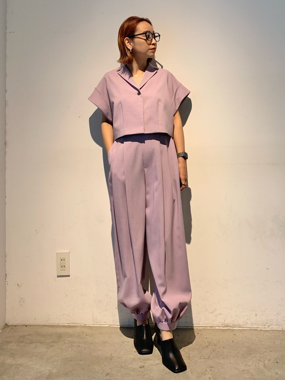 パープル系のテーラードジャケット、パープル系のスラックス、ブラック系のパンプスを着用したレディースの春コーディネートの3枚目の写真