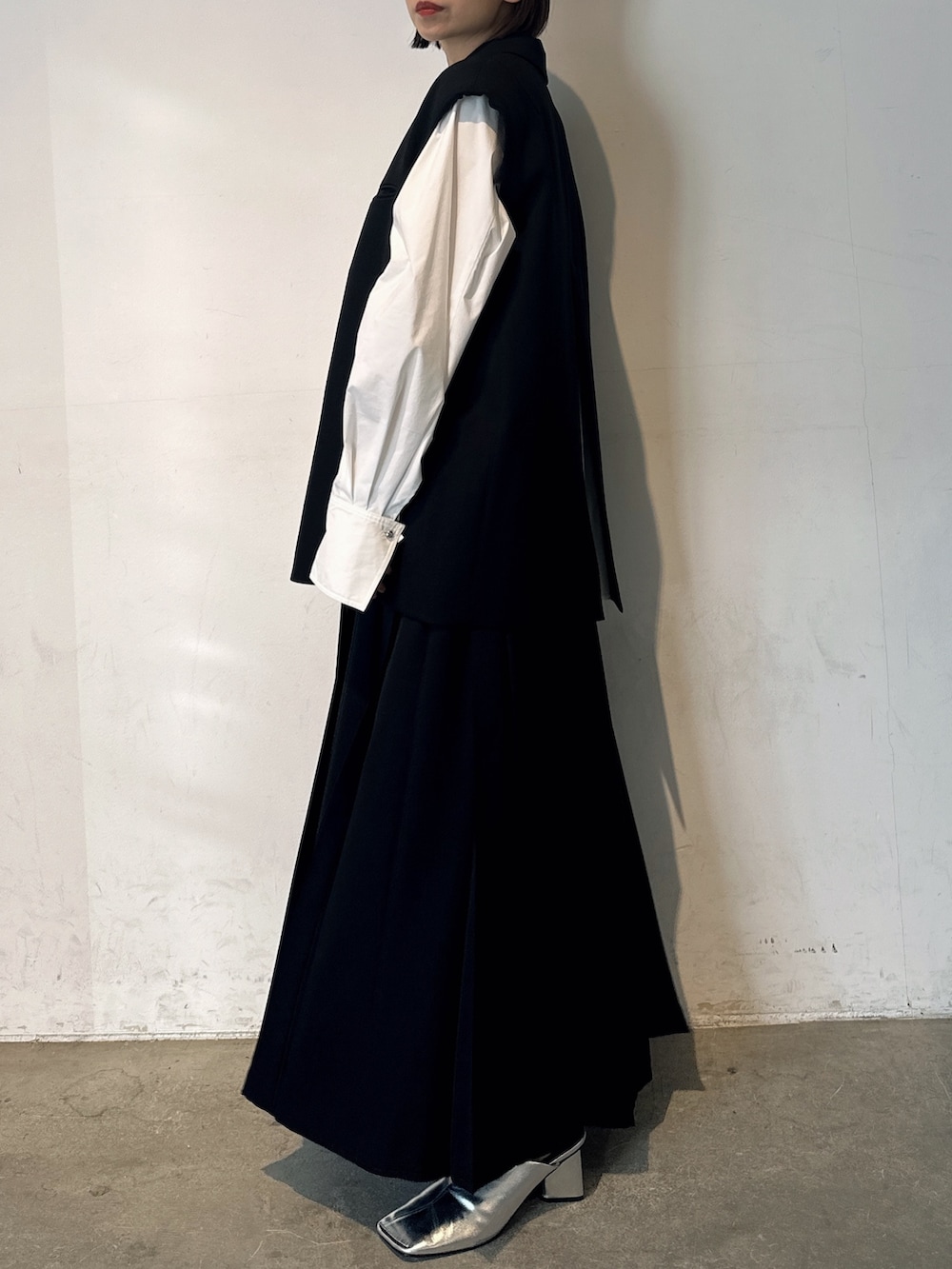 シルバー系のパンプス、ブラック系のテーラードジャケット、ブラック系のスカートを着用したレディースの冬コーディネートの4枚目の写真