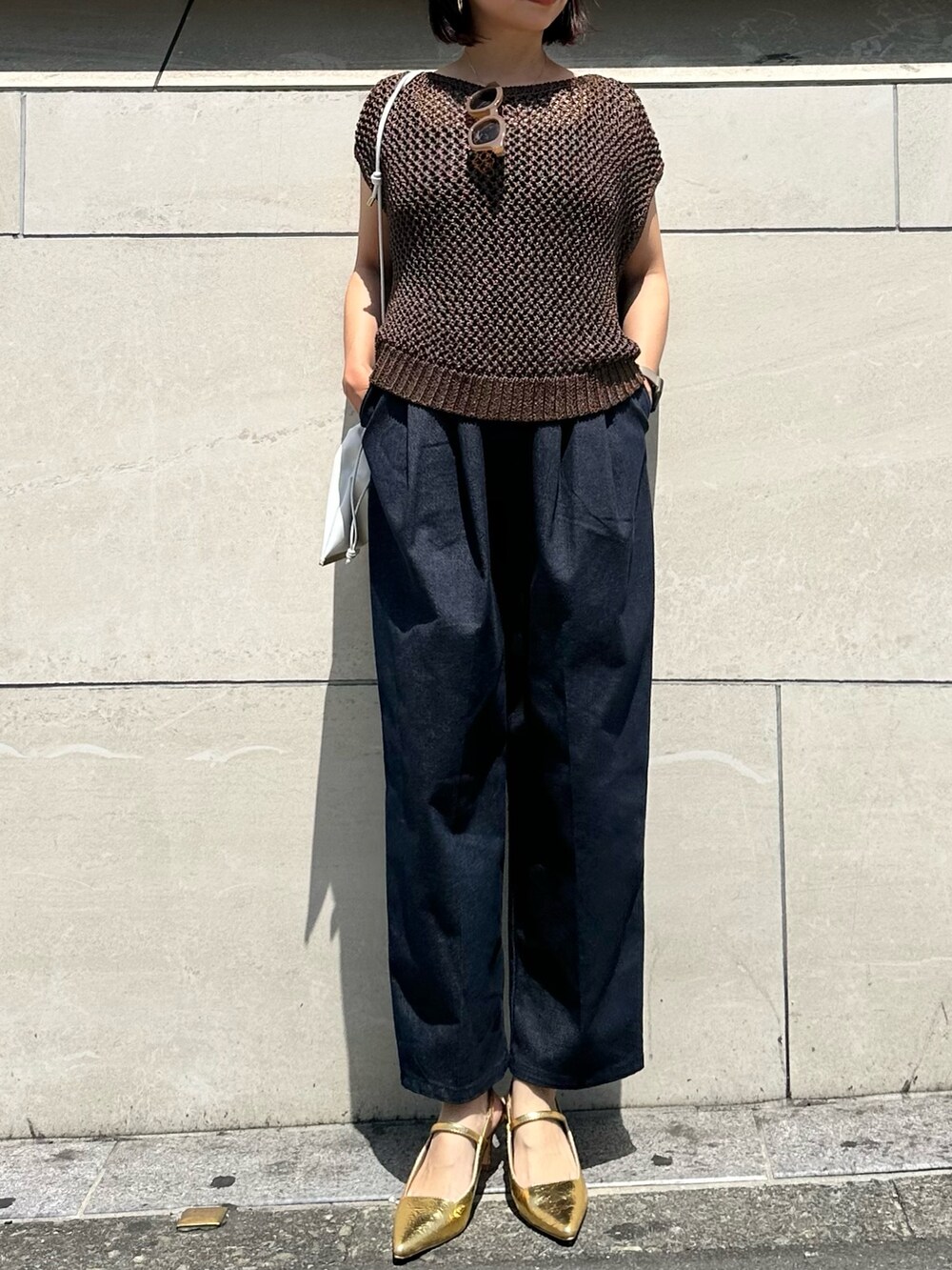 ブラウン系のニット/セーター、ブルー系のつなぎ/オールインワン、ゴールド系のサンダルを着用したレディースの春コーディネートの2枚目の写真