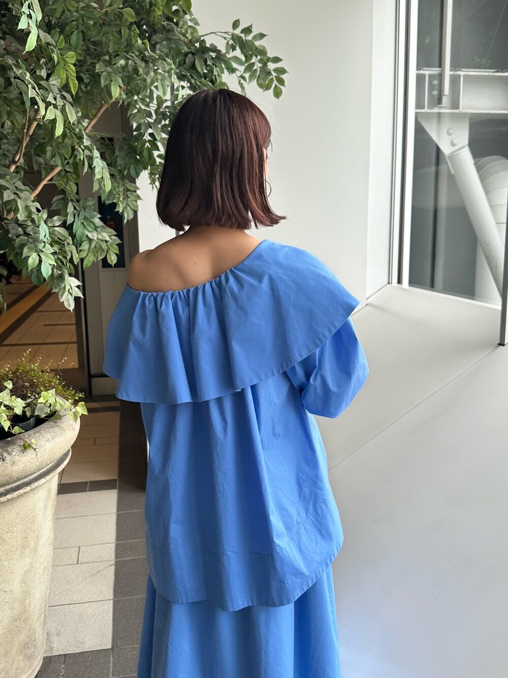 ブルー系のシャツ/ブラウス、ブルー系のスカート、ホワイト系のパンプスを着用したレディースの夏コーディネートの5枚目の写真