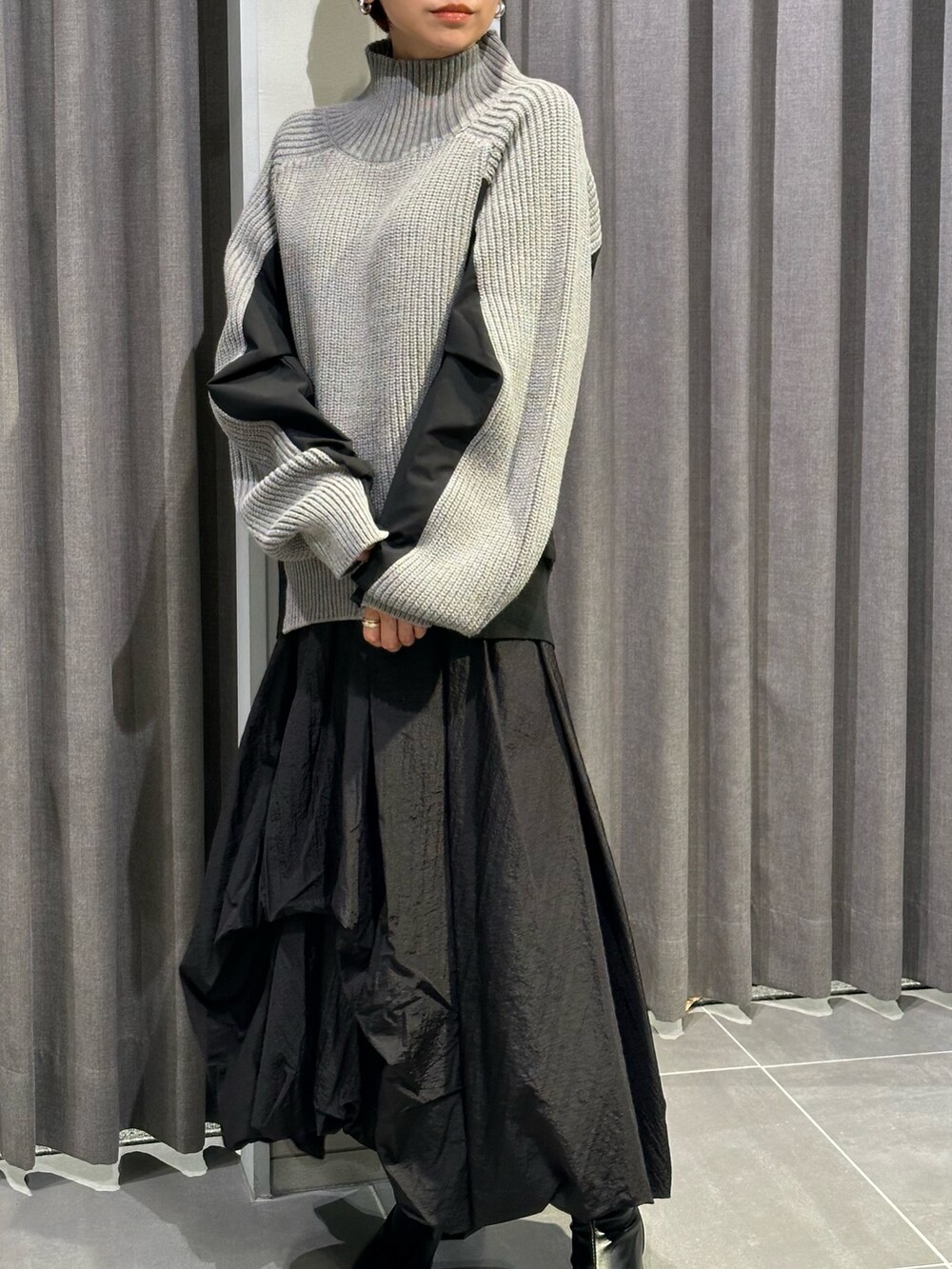 ブラック系のブーツ、ブラック系のスカート、グレー系のニット/セーターを着用したレディースの秋コーディネートの9枚目の写真