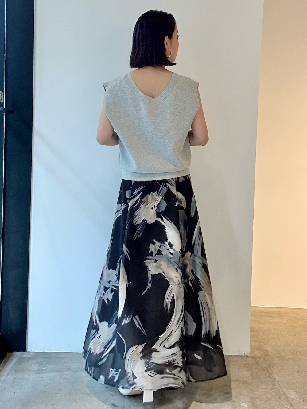 ブラック系のスカート、ホワイト系のサンダル、グレー系のニット/セーターを着用したレディースの春コーディネートの4枚目の写真