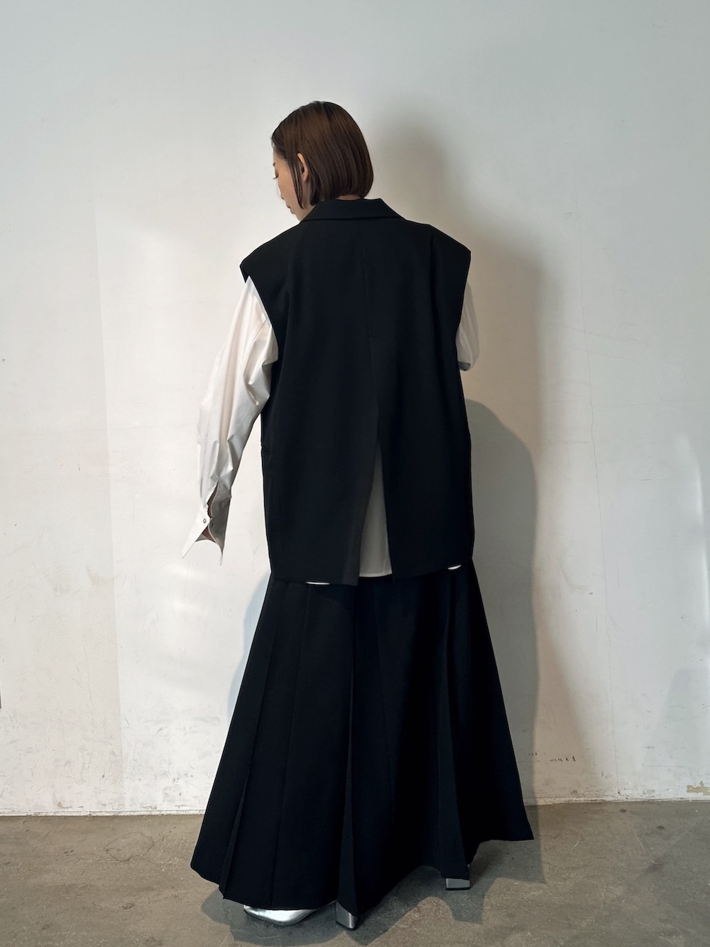 シルバー系のパンプス、ブラック系のテーラードジャケット、ブラック系のスカートを着用したレディースの冬コーディネートの5枚目の写真