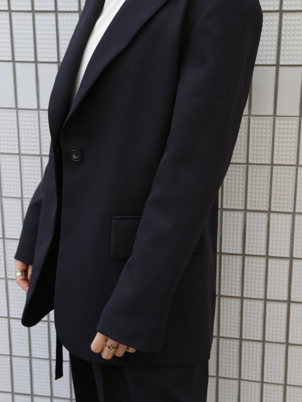 ブラック系のテーラードジャケット、ブラック系のその他パンツ、ホワイト系のスニーカーを着用したレディースの冬コーディネートの4枚目の写真