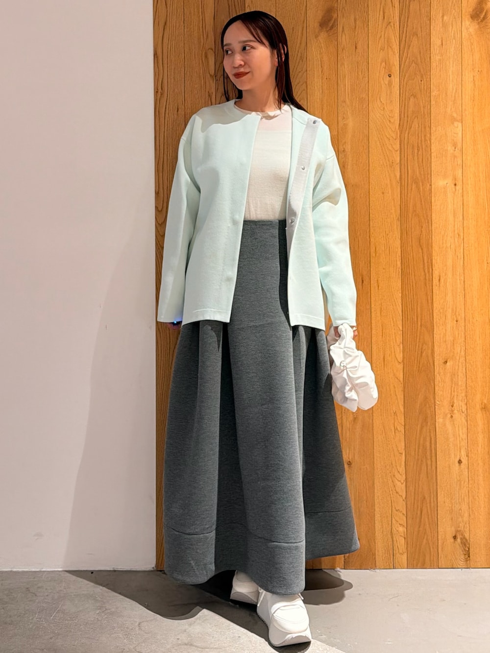 グレー系のスカート、ホワイト系のスニーカー、ホワイト系のハンドバッグを着用したレディースの冬コーディネートの2枚目の写真