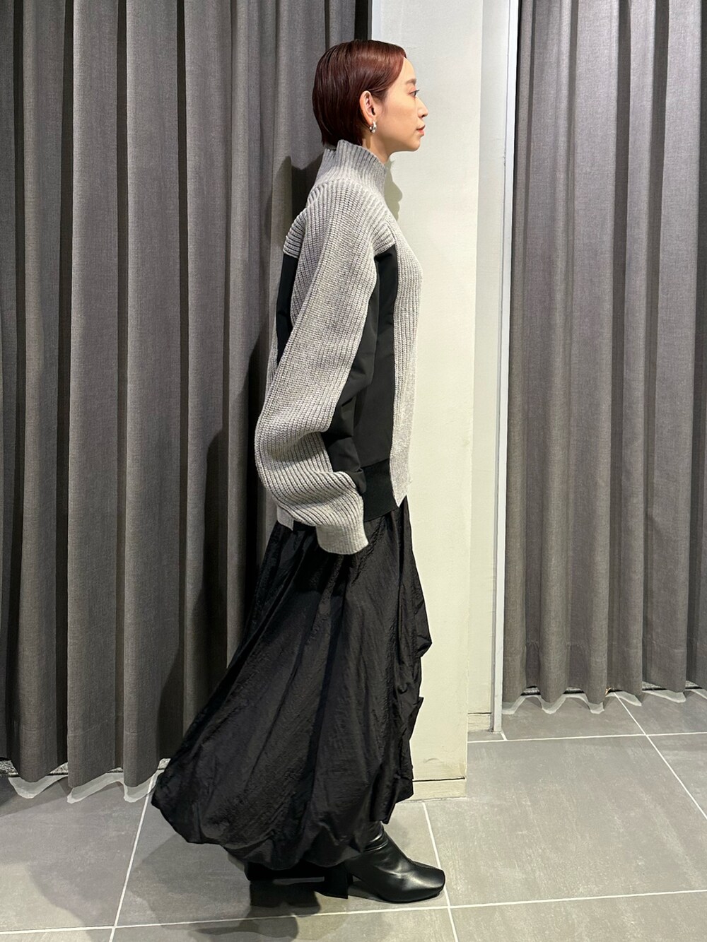 ブラック系のブーツ、ブラック系のスカート、グレー系のニット/セーターを着用したレディースの秋コーディネートの5枚目の写真