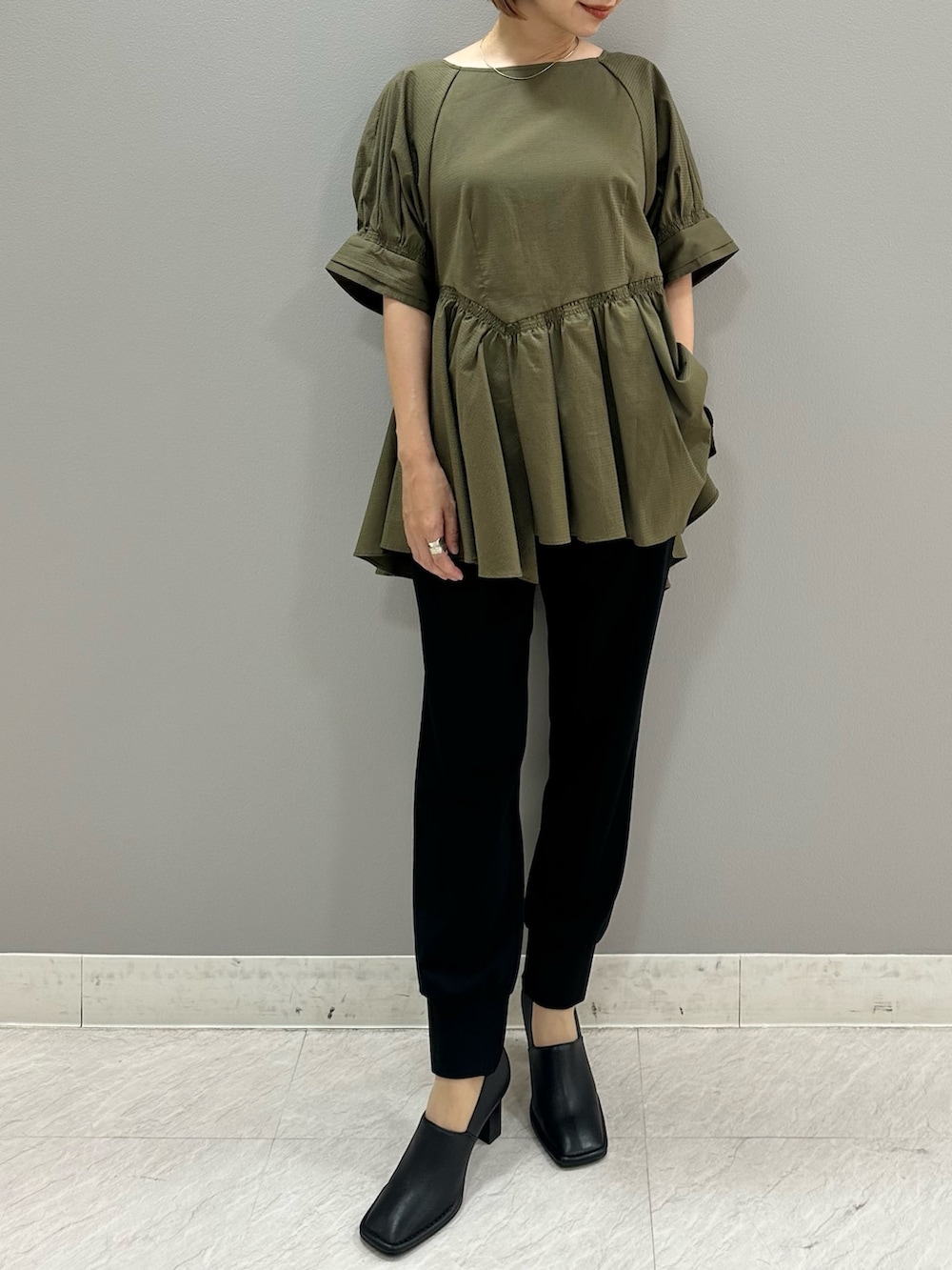 グリーン系のシャツ/ブラウス、ブラック系のスラックス、ブラック系のパンプスを着用したレディースの夏コーディネートの3枚目の写真