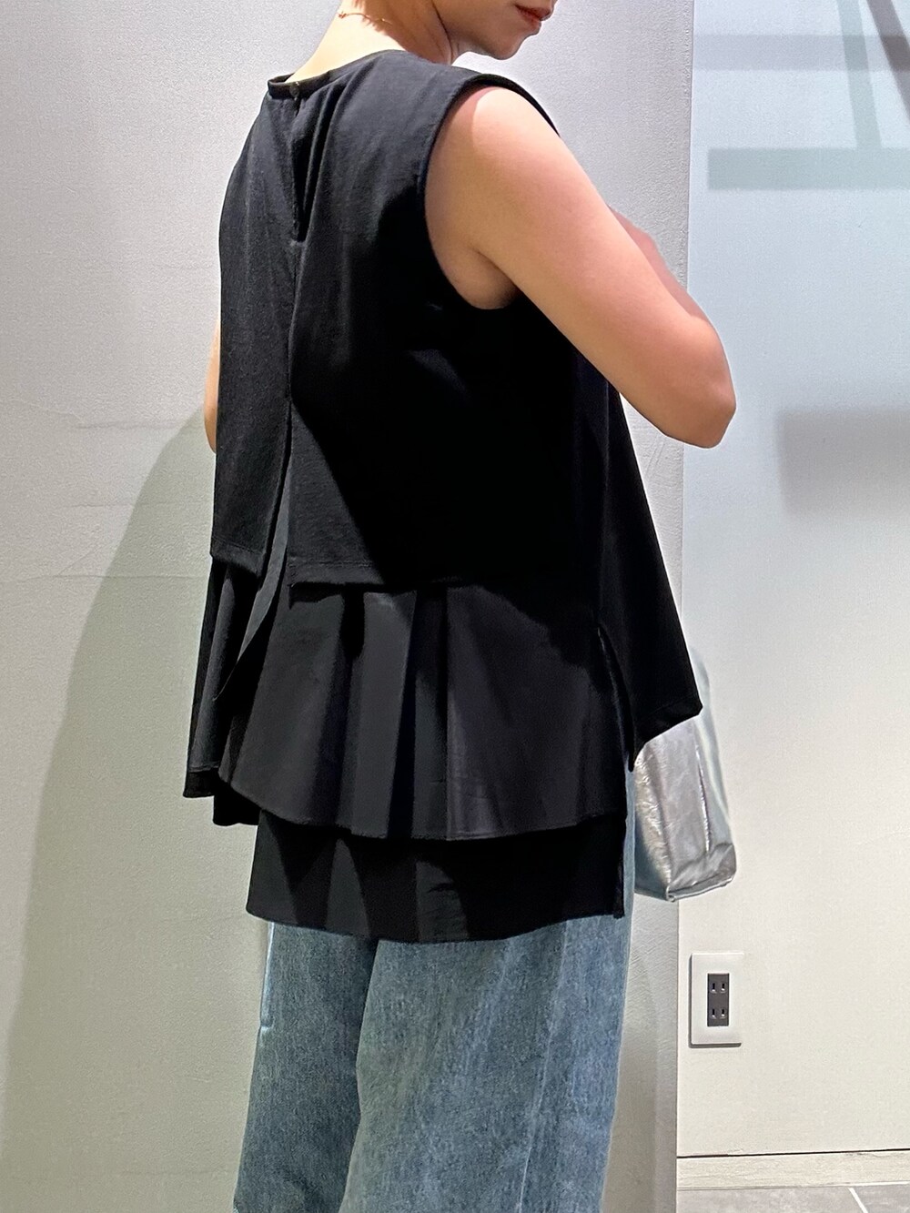 ブルー系のデニムパンツ、シルバー系のハンドバッグ、ブラック系のタンクトップを着用したレディースの夏コーディネートの7枚目の写真