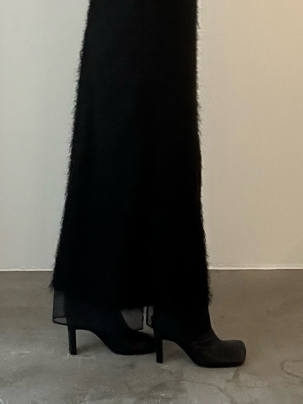 ブラック系のワンピース、シルバー系のハンドバッグ、ブラック系のブーツを着用したレディースの秋コーディネートの8枚目の写真