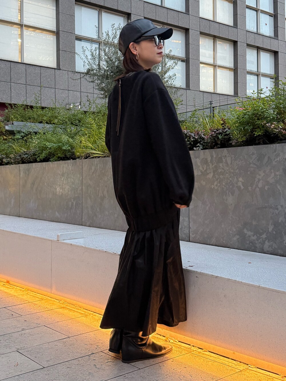 ブラック系のワンピース、ブラック系のブーツ、ブラック系のキャップを着用したレディースの冬コーディネートの2枚目の写真