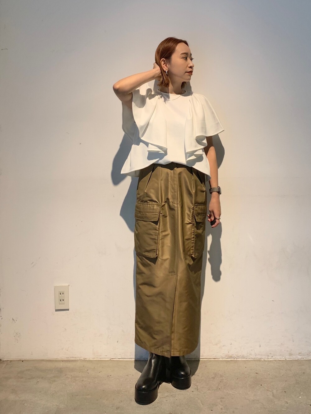 ホワイト系のTシャツ/カットソー、ブラウン系のスカート、ブラック系のブーツを着用したレディースの春コーディネートの2枚目の写真
