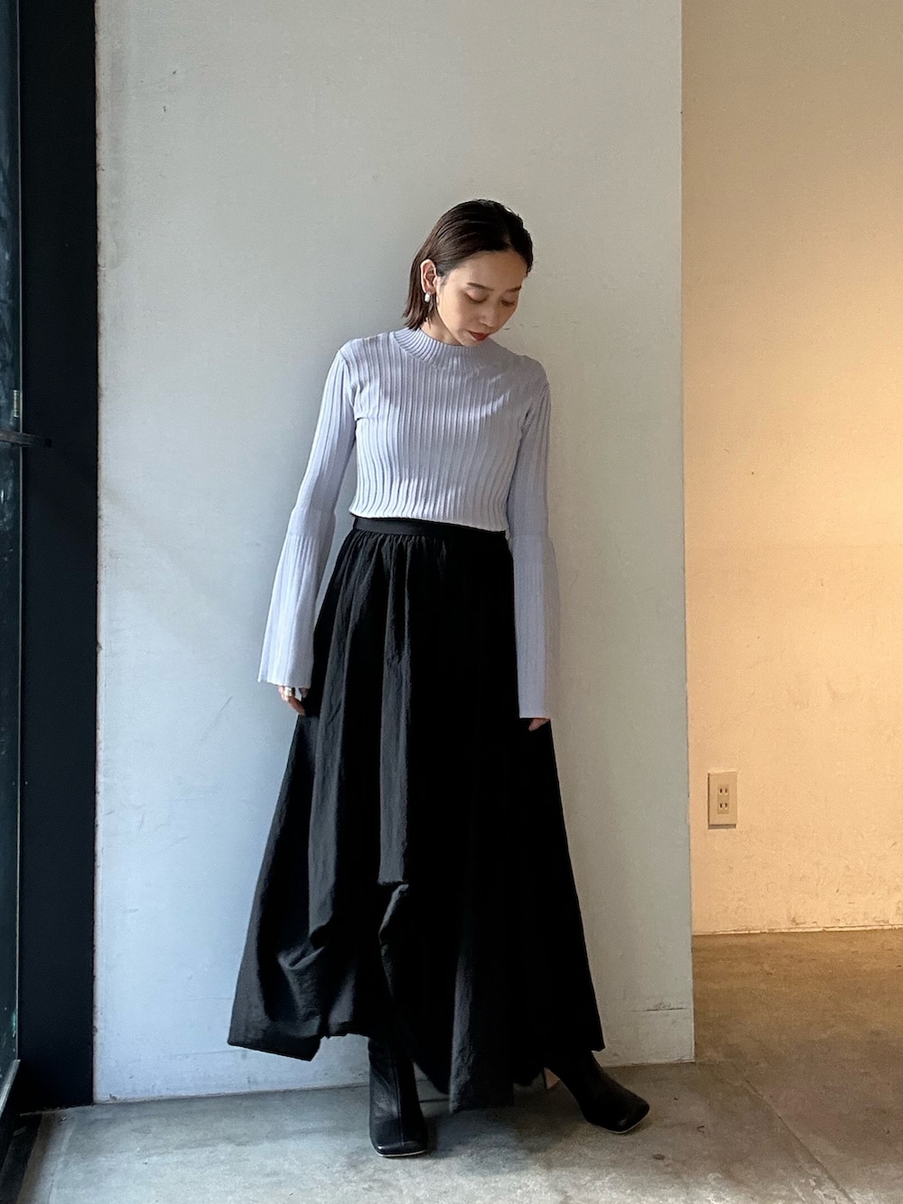 ブラック系のスカート、ブラック系のブーツ、パープル系のニット/セーターを着用したレディースの冬コーディネートの2枚目の写真