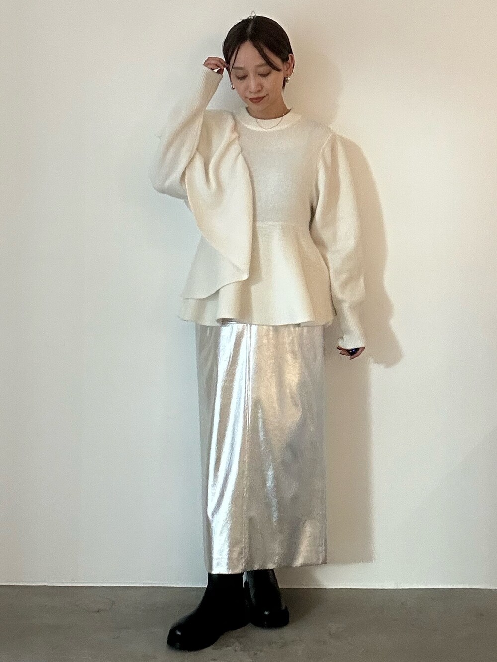 ホワイト系のニット/セーター、ブラック系のブーツ、シルバー系のスカートを着用したレディースの秋コーディネートの3枚目の写真