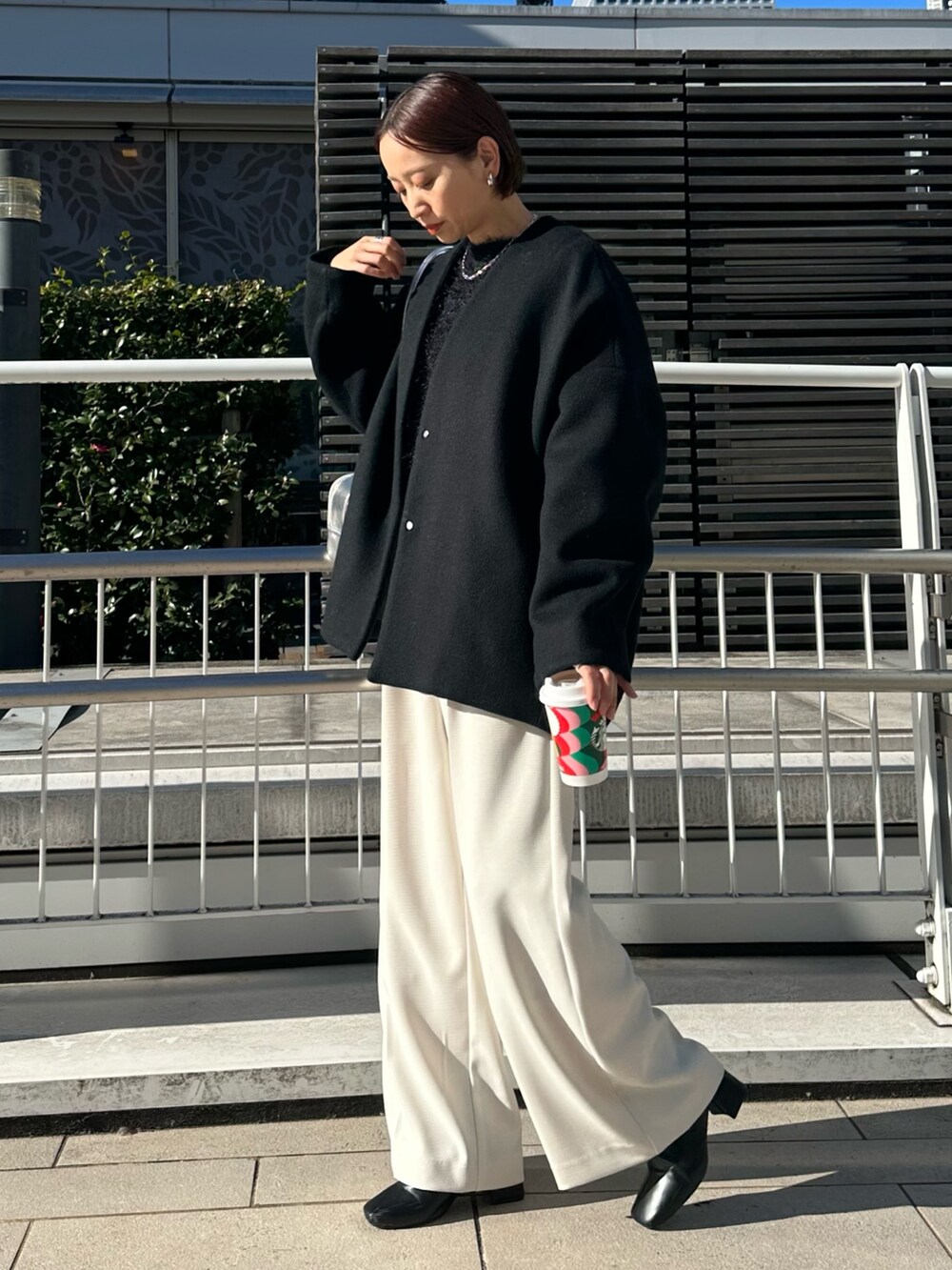 ブラック系のノーカラージャケット、シルバー系のボストンバッグ、ホワイト系のその他パンツを着用したレディースの冬コーディネートの3枚目の写真