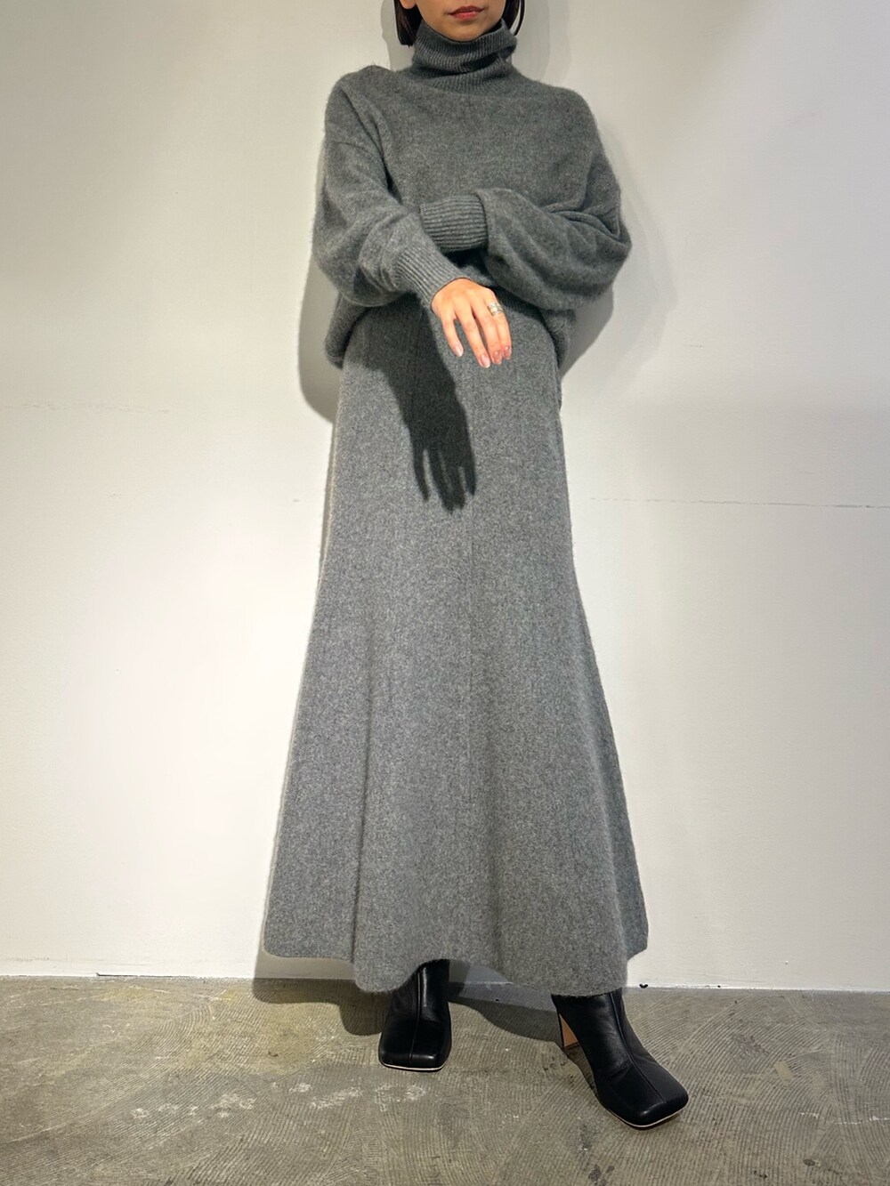 パープル系のノーカラージャケット、グレー系のスカート、ブラック系のブーツを着用したレディースの秋コーディネートの4枚目の写真