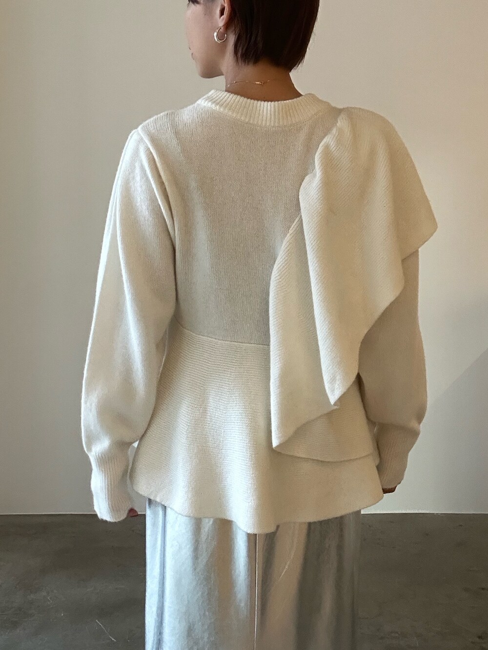 ホワイト系のニット/セーター、ブラック系のブーツ、シルバー系のスカートを着用したレディースの秋コーディネートの10枚目の写真