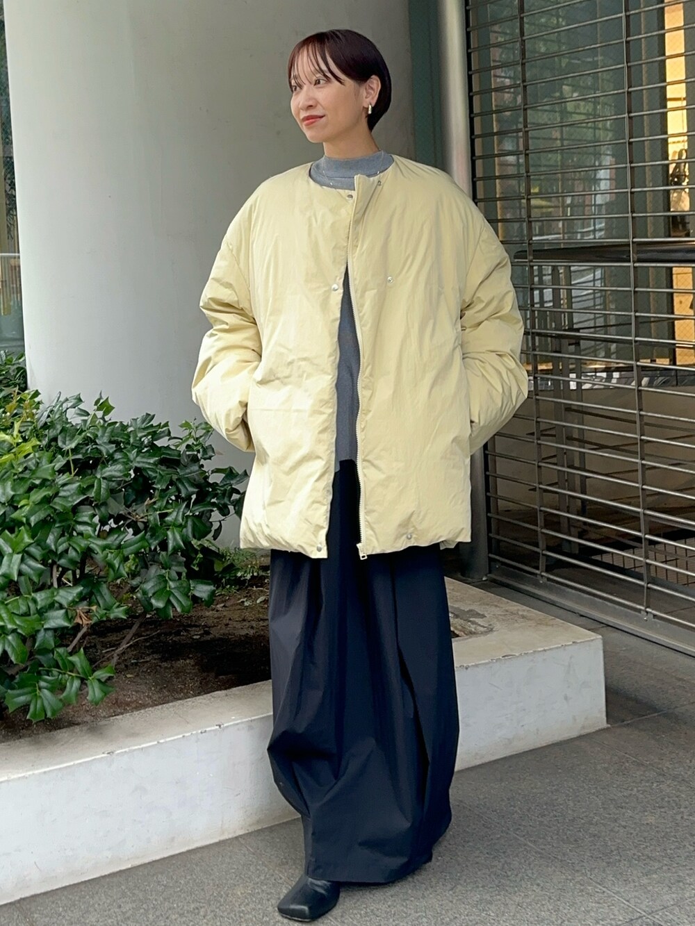 イエロー系のダウンジャケット/コート、グレー系のワンピース、ブラック系のブーツを着用したレディースの夏コーディネートの6枚目の写真