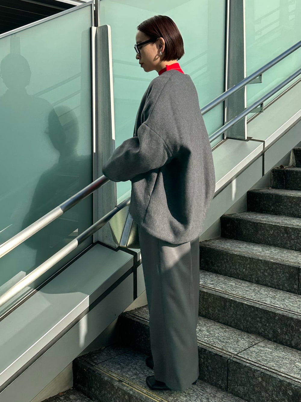 ブラック系のブーツ、グレー系のノーカラージャケット、レッド系のニット/セーターを着用したレディースの冬コーディネートの2枚目の写真