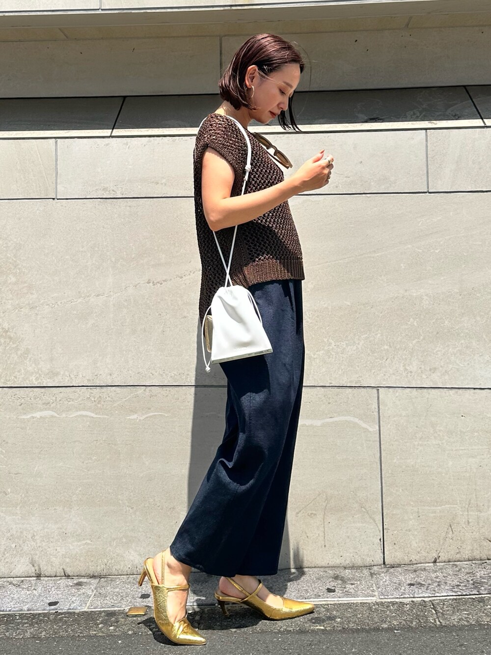 ブラウン系のニット/セーター、ブルー系のつなぎ/オールインワン、ゴールド系のサンダルを着用したレディースの春コーディネートの3枚目の写真