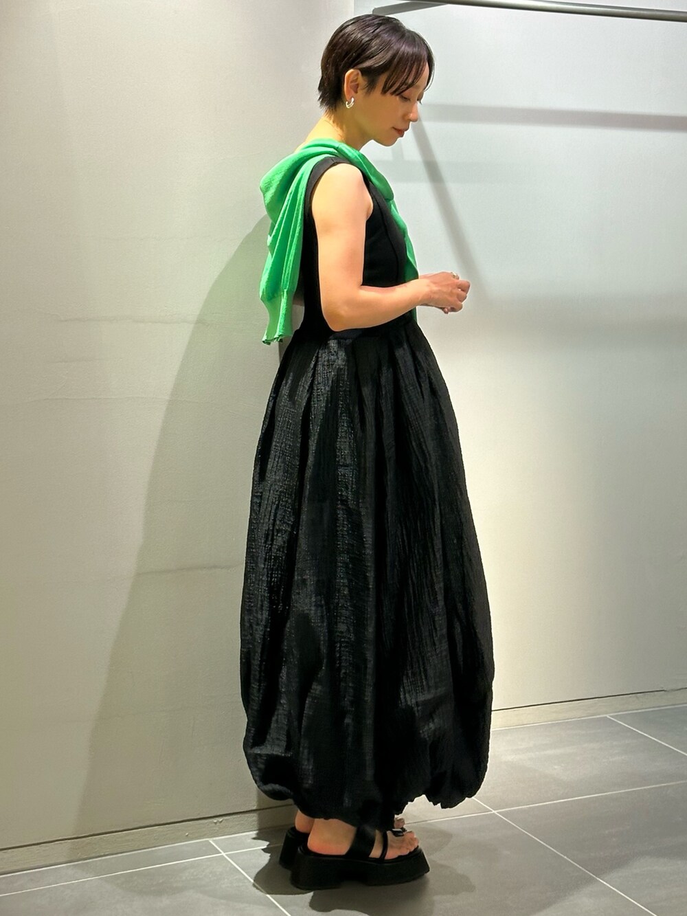 ブラック系のワンピース、ブラック系のサンダル、グリーン系のカーディガン/ボレロを着用したレディースの夏コーディネートの5枚目の写真