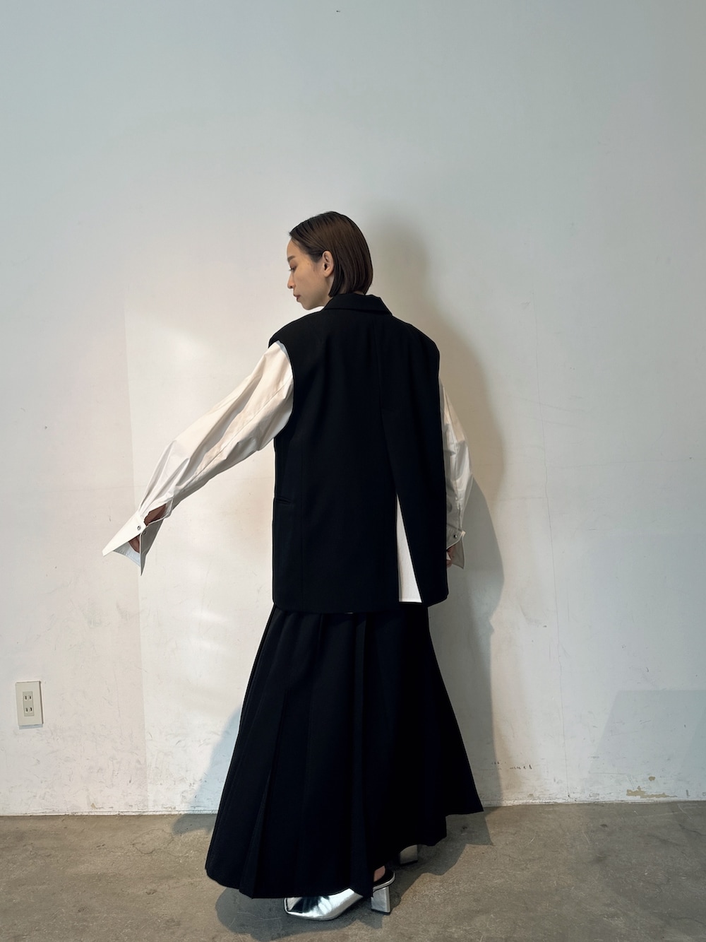 シルバー系のパンプス、ブラック系のテーラードジャケット、ブラック系のスカートを着用したレディースの冬コーディネートの3枚目の写真