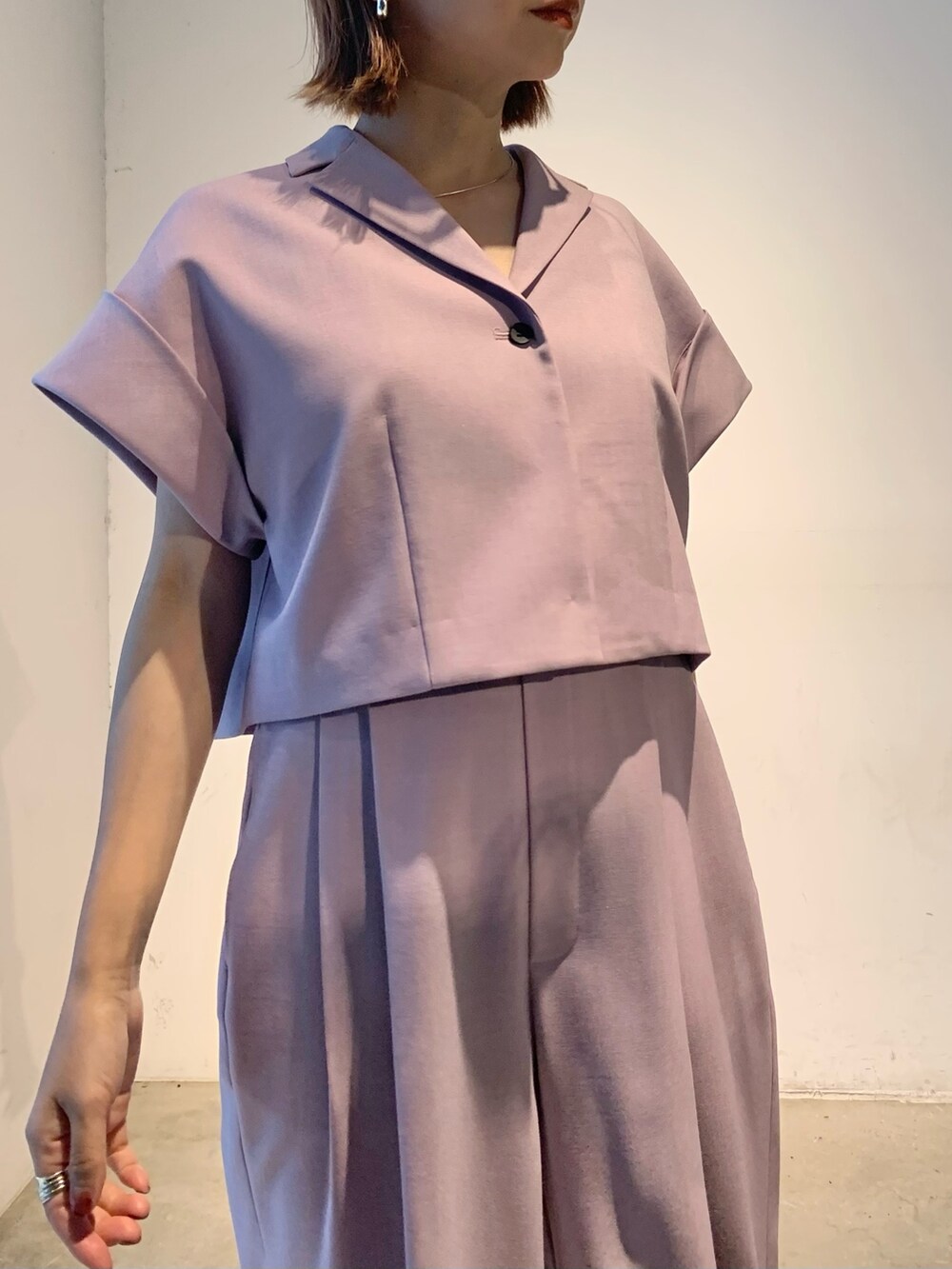 パープル系のテーラードジャケット、パープル系のスラックス、ブラック系のパンプスを着用したレディースの春コーディネートの6枚目の写真