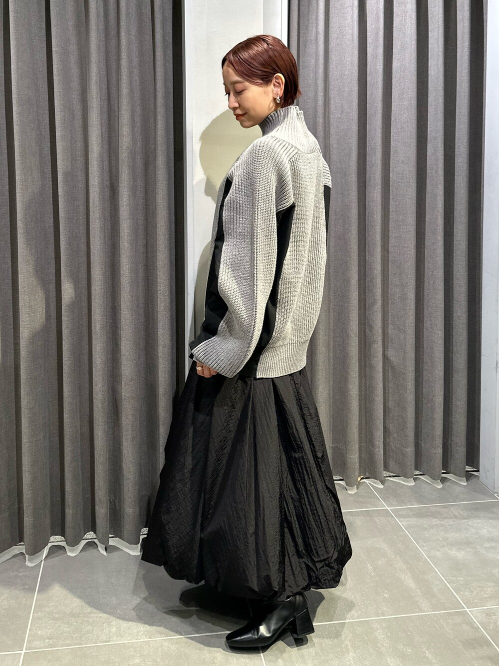 ブラック系のブーツ、ブラック系のスカート、グレー系のニット/セーターを着用したレディースの秋コーディネートの4枚目の写真