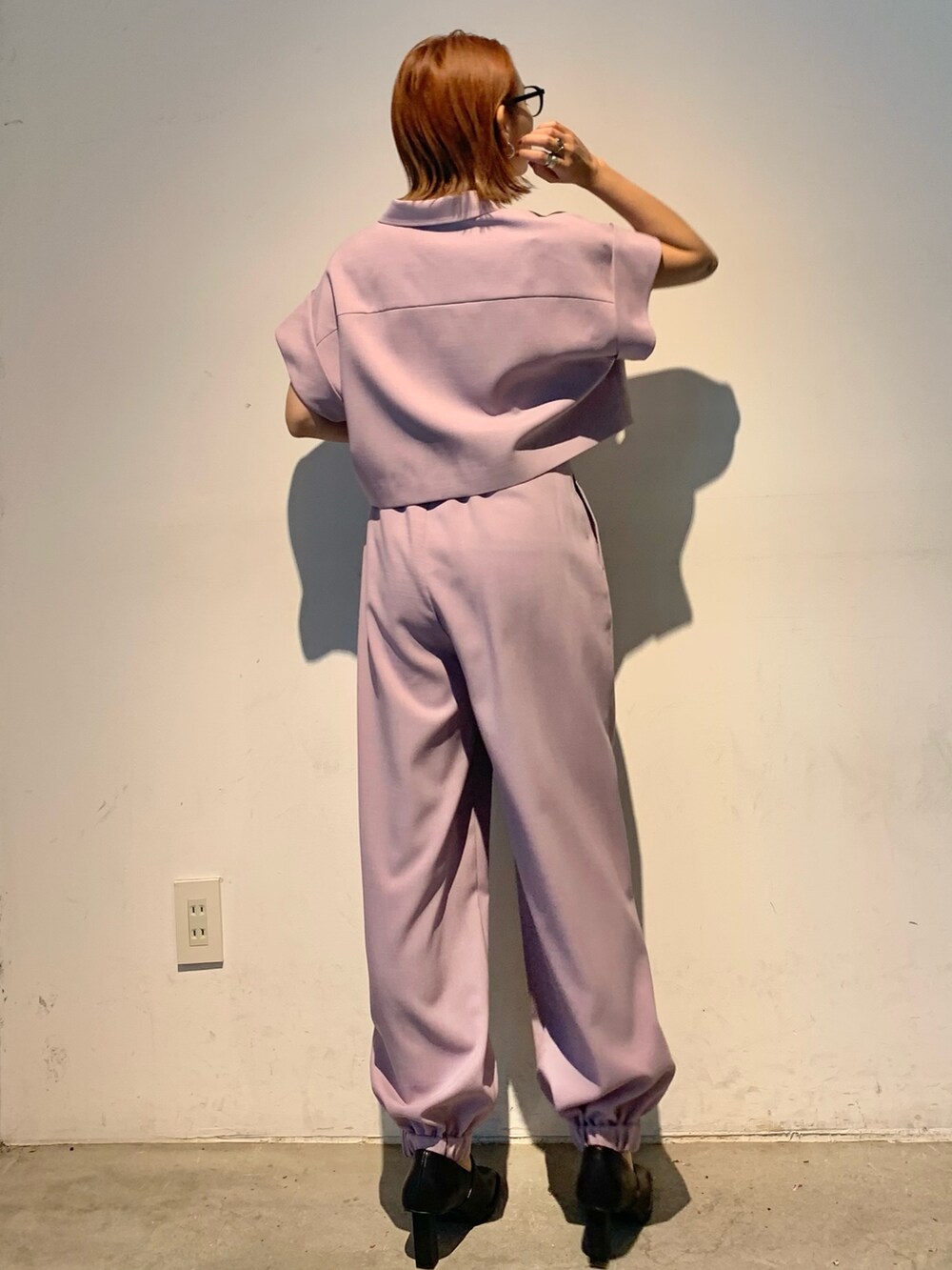 パープル系のテーラードジャケット、パープル系のスラックス、ブラック系のパンプスを着用したレディースの春コーディネートの5枚目の写真