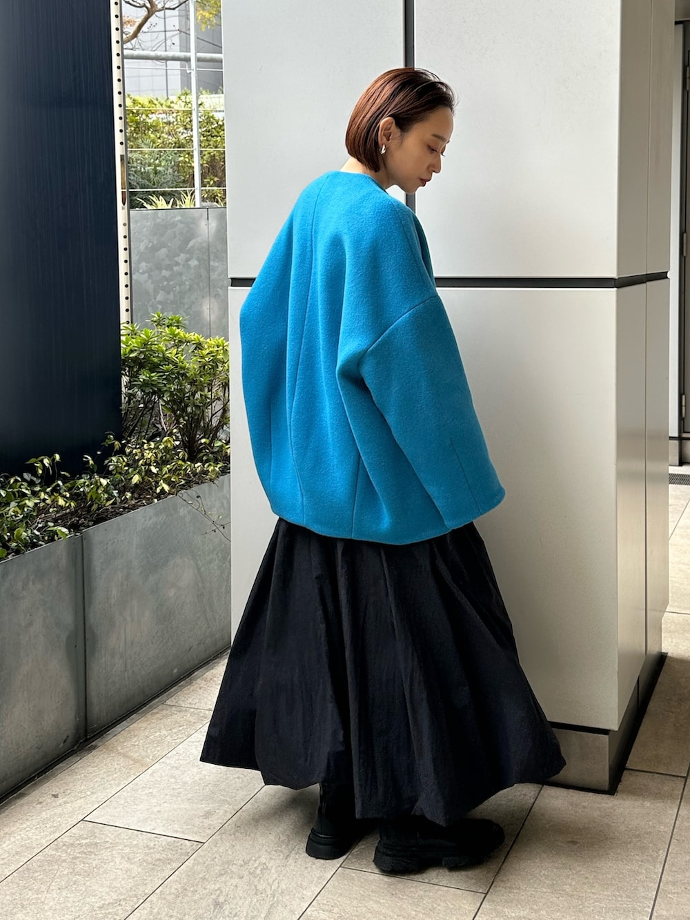 ブルー系のノーカラーコート、ブラック系のスカート、ホワイト系のニット/セーターを着用したレディースの冬コーディネートの5枚目の写真