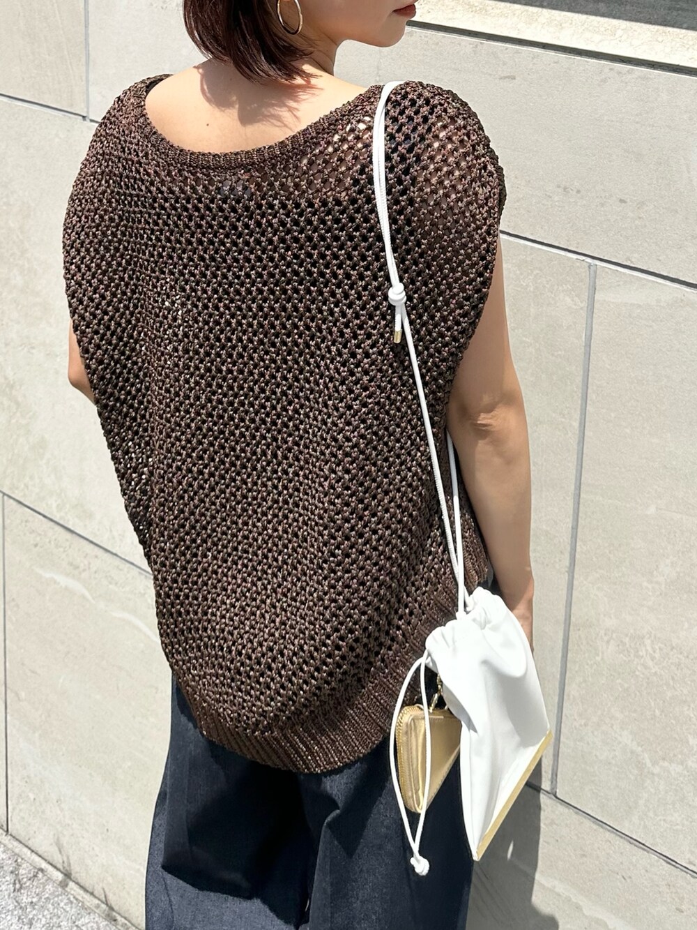 ブラウン系のニット/セーター、ブルー系のつなぎ/オールインワン、ゴールド系のサンダルを着用したレディースの春コーディネートの5枚目の写真