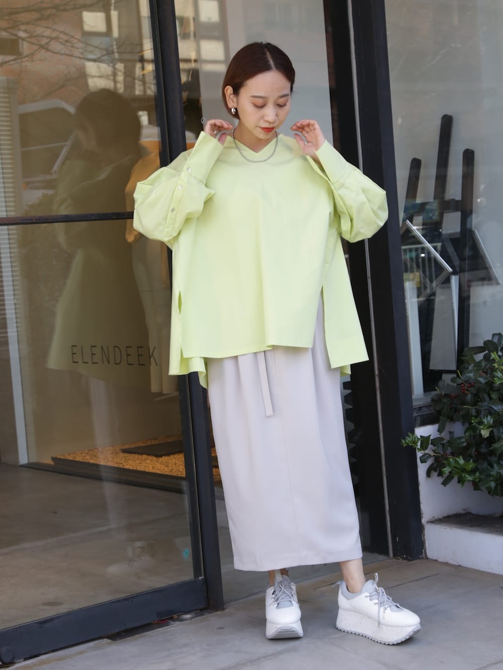 ベージュ系のスカート、ホワイト系のスニーカー、イエロー系のシャツ/ブラウスを着用したレディースの冬コーディネートの3枚目の写真