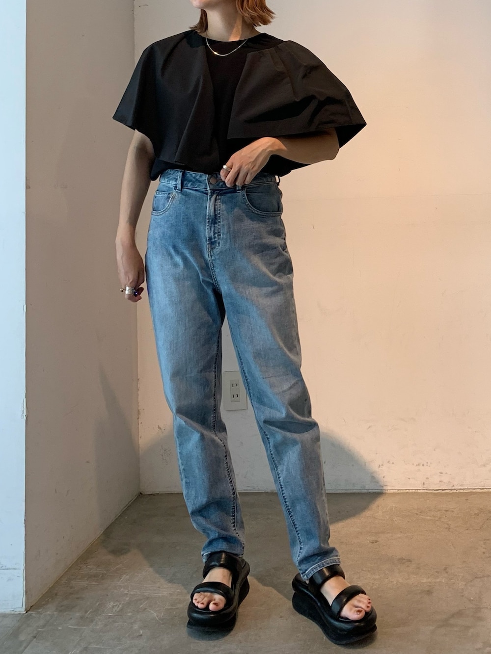ブラック系のTシャツ/カットソー、ブルー系のデニムパンツ、ブラック系のサンダルを着用したレディースの春コーディネートの3枚目の写真