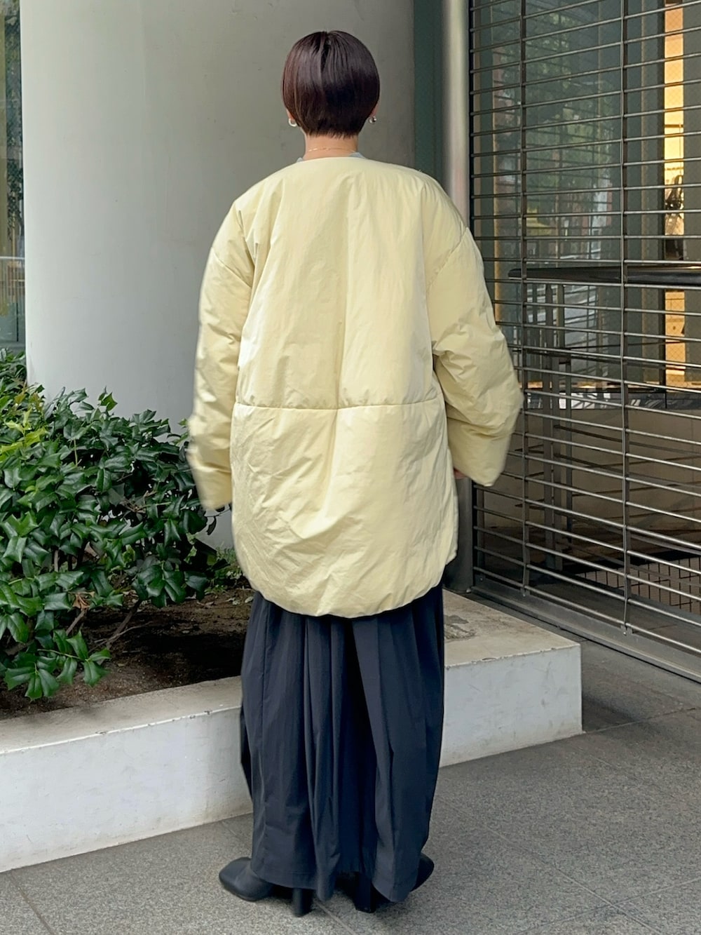 イエロー系のダウンジャケット/コート、グレー系のワンピース、ブラック系のブーツを着用したレディースの夏コーディネートの7枚目の写真