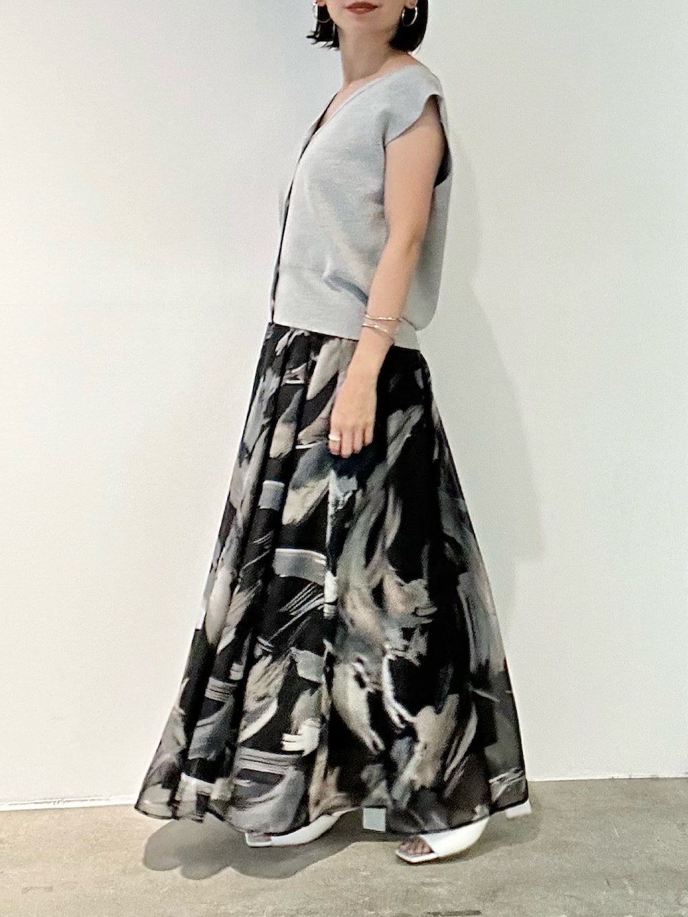 ブラック系のスカート、ホワイト系のサンダル、グレー系のニット/セーターを着用したレディースの春コーディネートの3枚目の写真