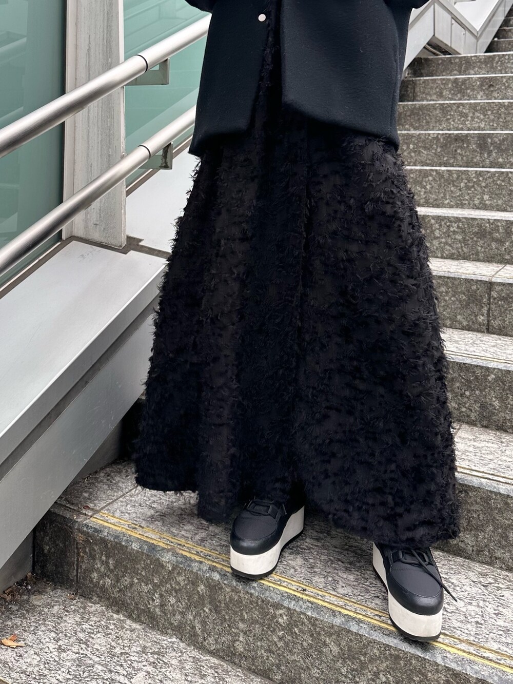 ブラック系のスニーカー、ブラック系のワンピース、ブラック系のニット/セーターを着用したレディースの冬コーディネートの10枚目の写真