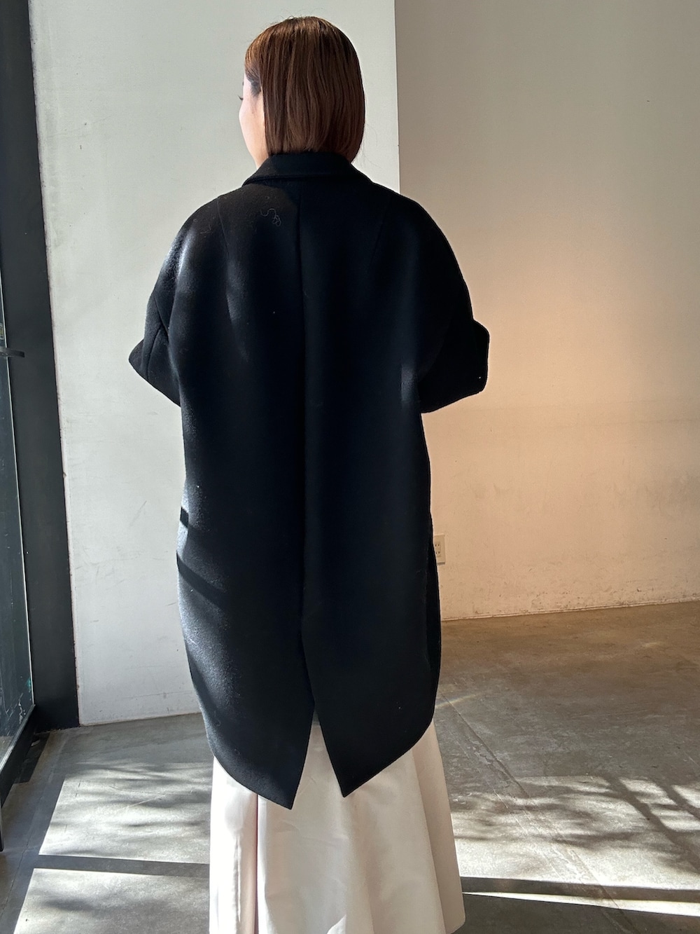 グレー系のワンピース、ブラック系のブーツ、ブラック系のチェスターコートを着用したレディースの冬コーディネートの6枚目の写真