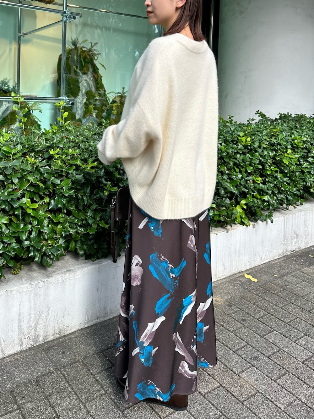 ホワイト系のニット/セーター、ブラウン系のスカート、ブラウン系のボストンバッグを着用したレディースの秋コーディネートの3枚目の写真