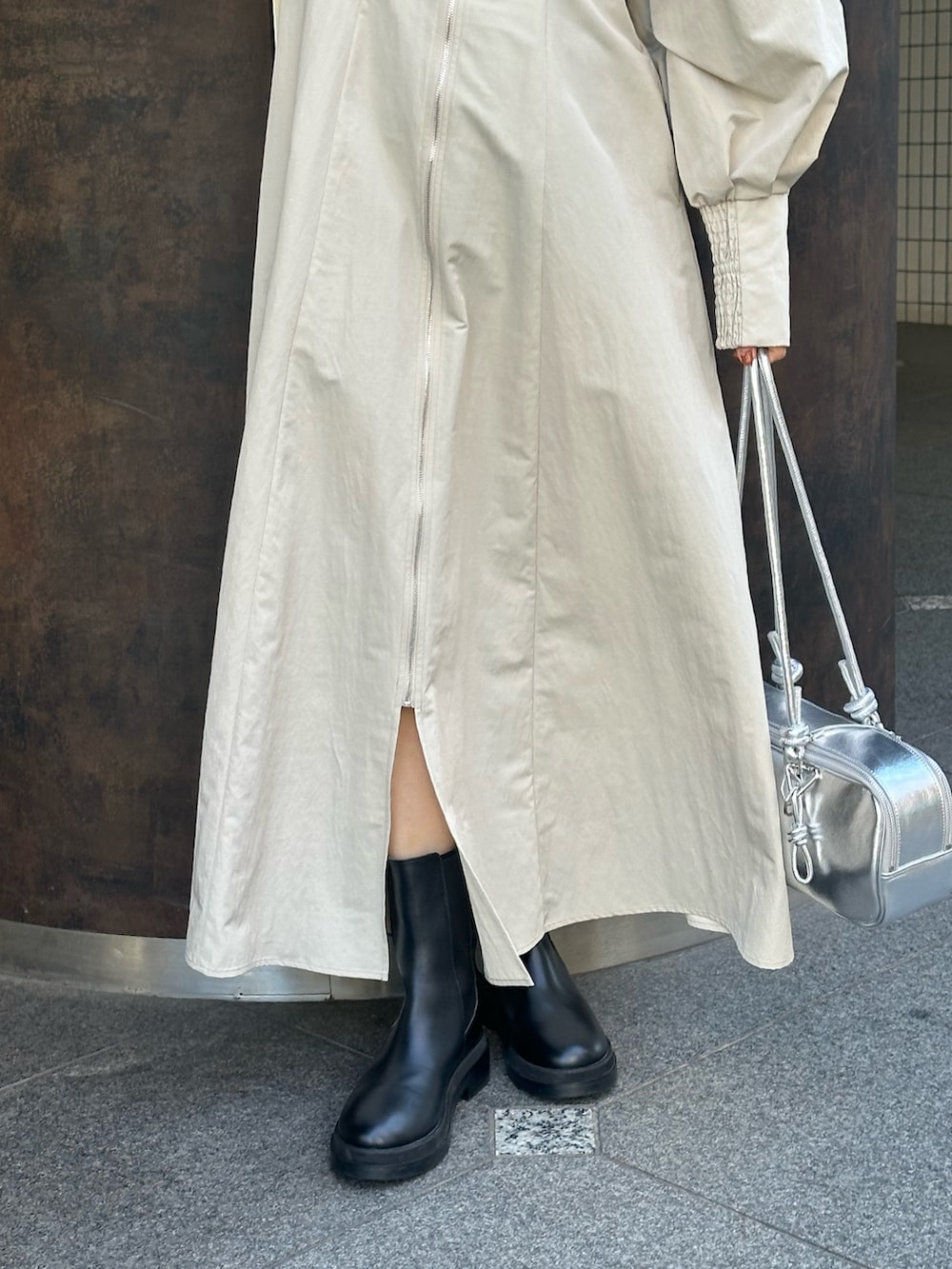 シルバー系のボストンバッグ、ブラック系のブーツ、ベージュ系のワンピースを着用したレディースの冬コーディネートの7枚目の写真