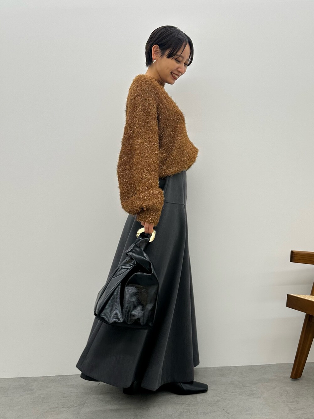 オレンジ系のニット/セーター、グレー系のスカート、ブラック系のブーツを着用したレディースの秋コーディネートの3枚目の写真