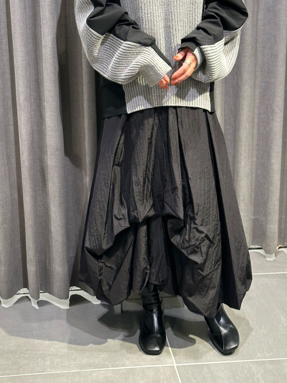 ブラック系のブーツ、ブラック系のスカート、グレー系のニット/セーターを着用したレディースの秋コーディネートの7枚目の写真