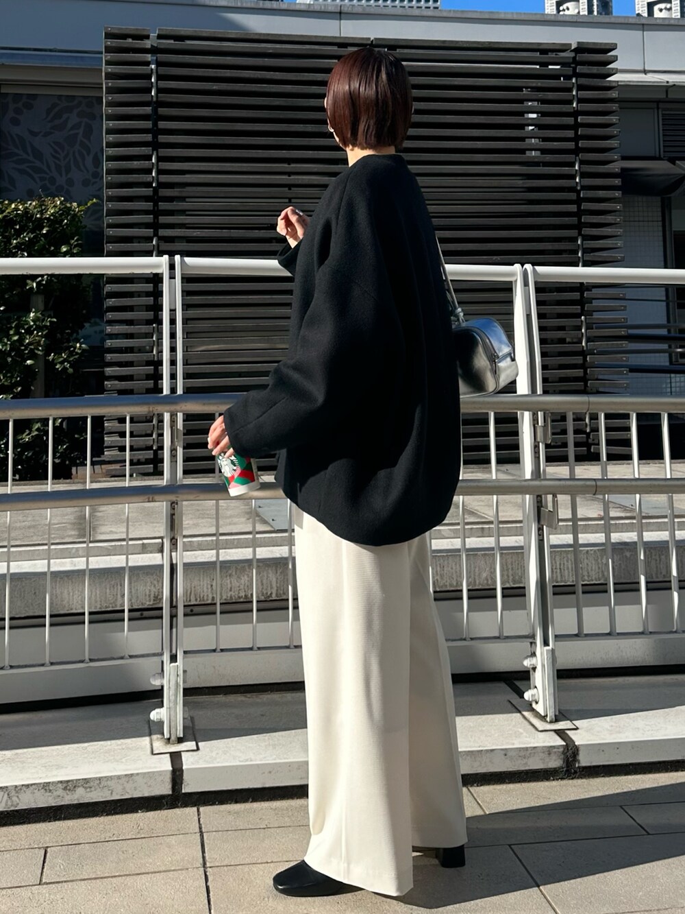 ブラック系のノーカラージャケット、シルバー系のボストンバッグ、ホワイト系のその他パンツを着用したレディースの冬コーディネートの5枚目の写真