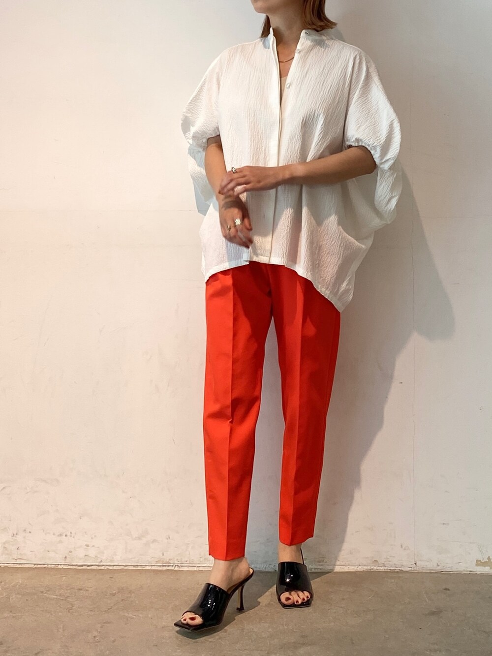 レッド系のその他パンツ、ホワイト系のシャツ/ブラウス、ブラック系のサンダルを着用したレディースの春コーディネートの2枚目の写真