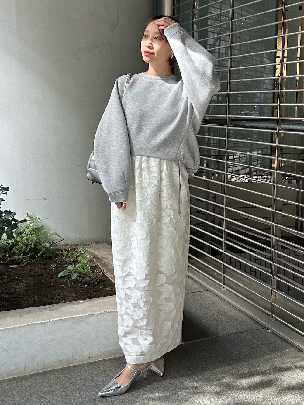 グレー系のスウェット、ホワイト系のスカート、シルバー系のボストンバッグを着用したレディースの冬コーディネートの3枚目の写真