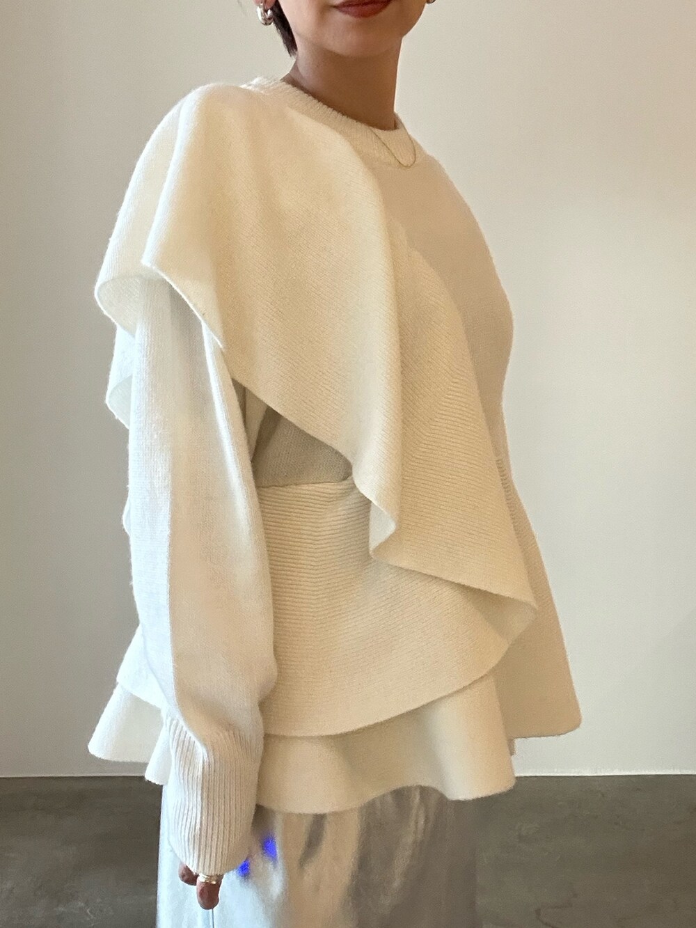 ホワイト系のニット/セーター、ブラック系のブーツ、シルバー系のスカートを着用したレディースの秋コーディネートの9枚目の写真