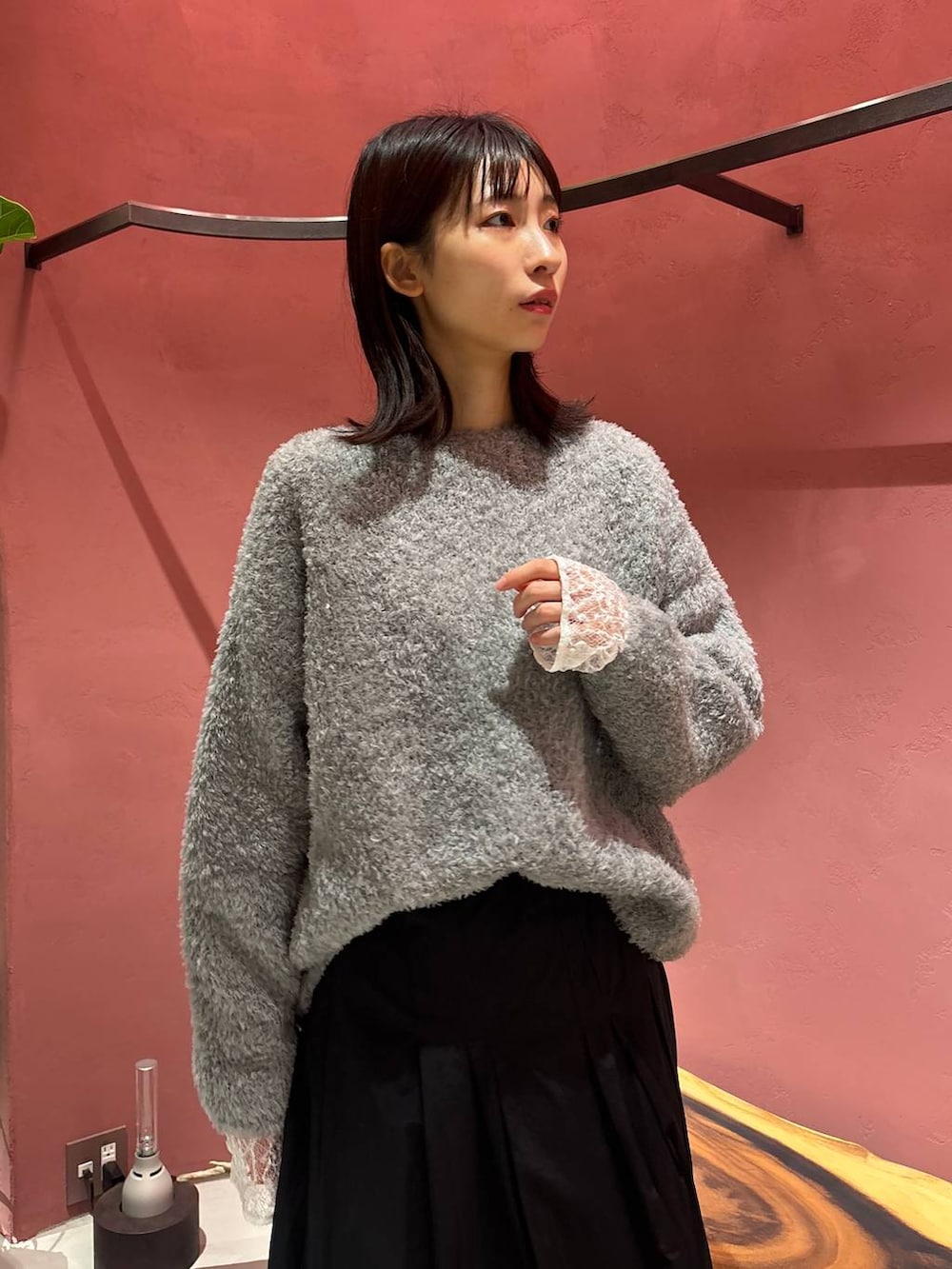 グレー系のニット/セーター、ホワイト系のTシャツ/カットソー、ブラック系のチェスターコートを着用したレディースの秋コーディネートの6枚目の写真