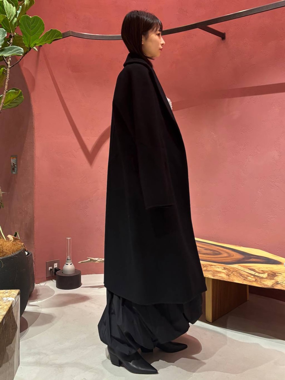 グレー系のニット/セーター、ホワイト系のTシャツ/カットソー、ブラック系のチェスターコートを着用したレディースの秋コーディネートの4枚目の写真