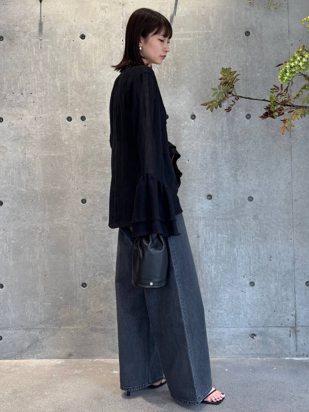 グレー系のチューブトップ、ブラック系のデニムパンツ、ブルー系のニット/セーターを着用したレディースの夏コーディネートの2枚目の写真