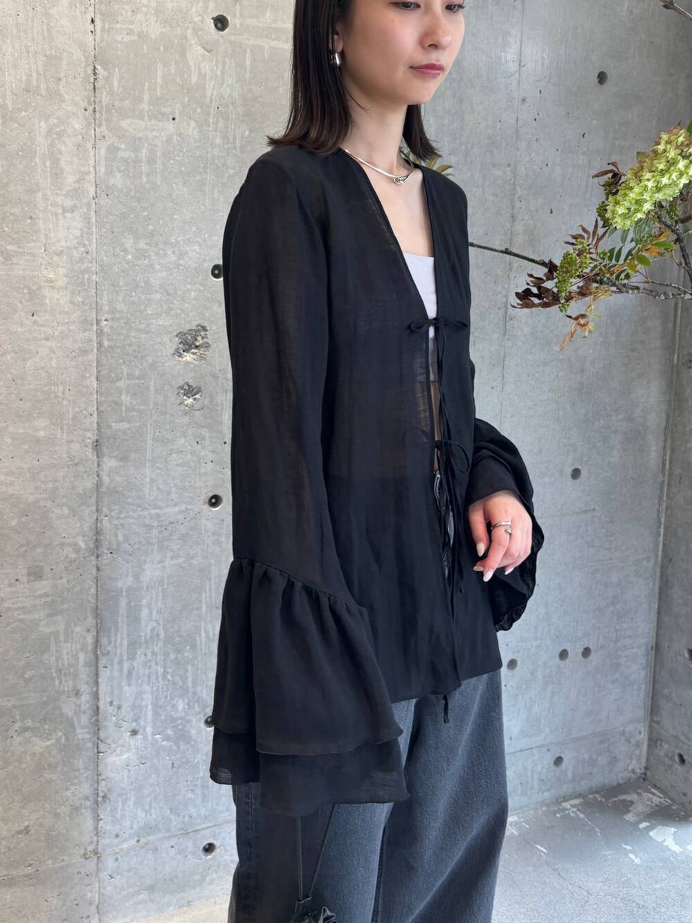 グレー系のチューブトップ、ブラック系のデニムパンツ、ブルー系のニット/セーターを着用したレディースの夏コーディネートの7枚目の写真