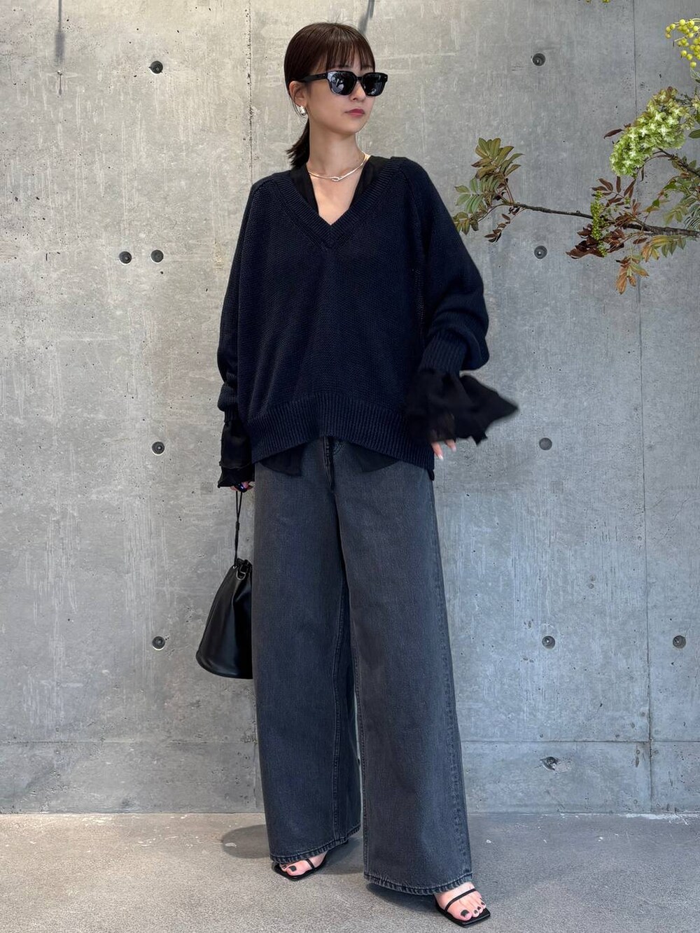 グレー系のチューブトップ、ブラック系のデニムパンツ、ブルー系のニット/セーターを着用したレディースの夏コーディネートの4枚目の写真